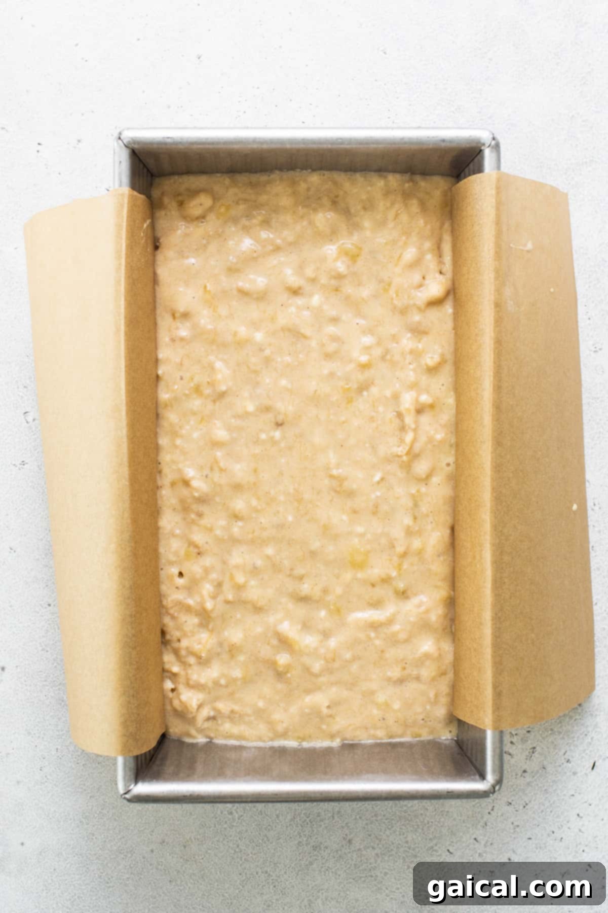 Protein-Boosted Banana Bread 5 Freshly baked protein banana bread in a loaf pan on a white surface, cooling down.
