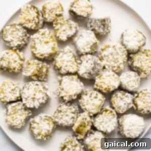 Perfectly crispy breaded air fryer pickles neatly arranged in a single layer within an air fryer basket, ready to be cooked to golden perfection.