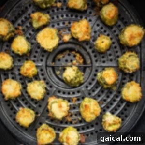 A close-up view of golden-brown air fryer pickles cooking perfectly inside an air fryer basket, showing their irresistible crispiness.