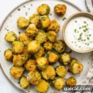 A vibrant plate of freshly air-fried pickles presented with a small bowl of creamy, homemade dipping sauce, inviting you to enjoy this delicious snack or appetizer.