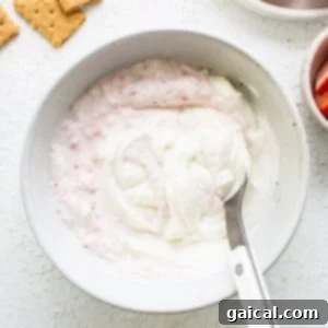 Creamy Protein Strawberry Cheesecake Jars 9 A bowl of yogurt with strawberries and crackers.