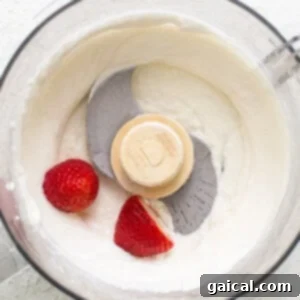 Creamy Protein Strawberry Cheesecake Jars 8 A food processor with whipped cream and strawberries.