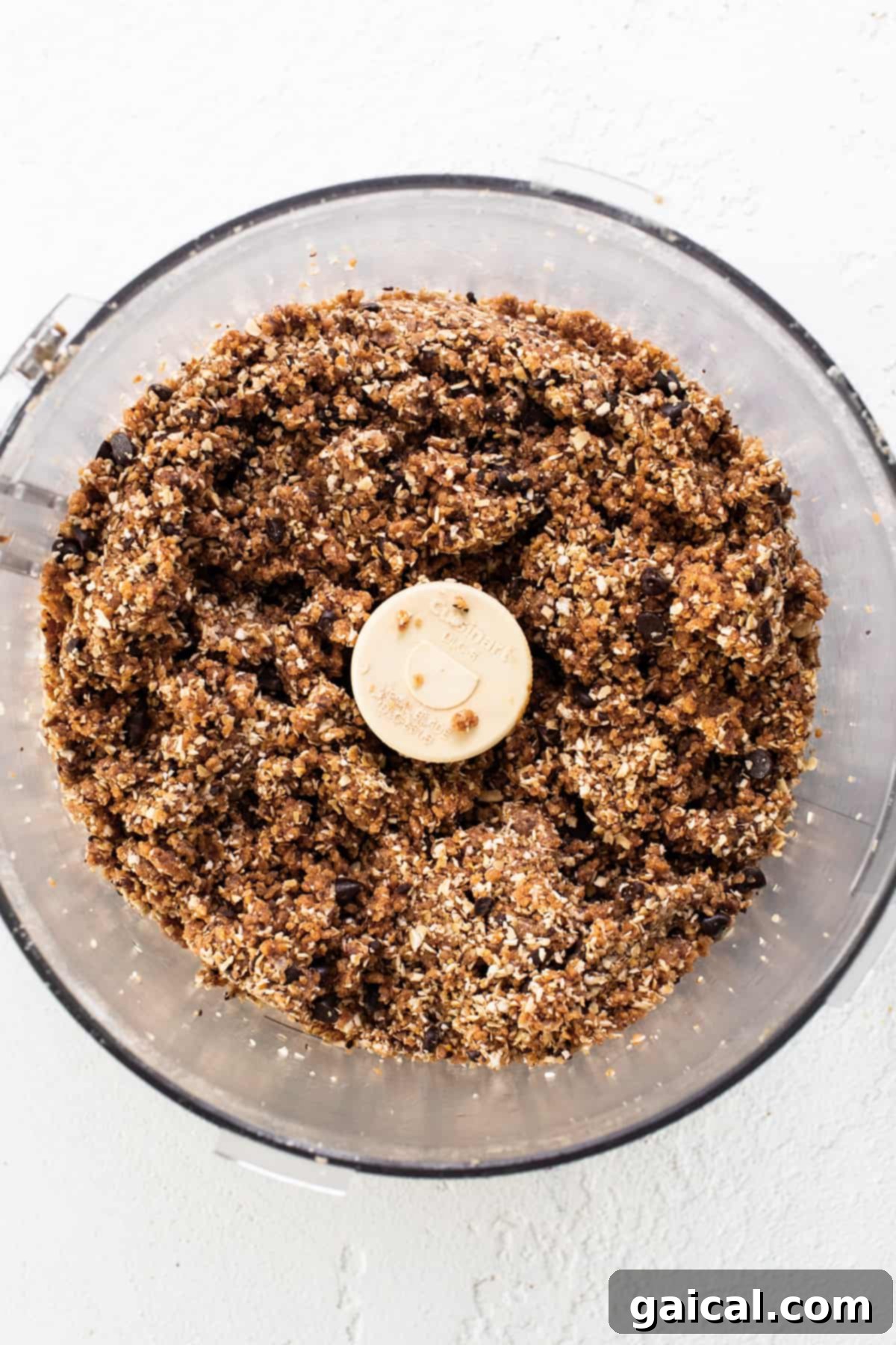 Healthy Protein Cookie Dough Bites 5 A food processor containing a thick, chunky mixture, resembling cookie dough, with chocolate chips visible.