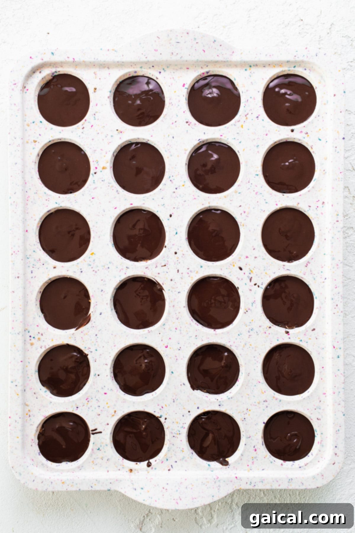 Healthy Protein Cookie Dough Bites 6 A tray filled with mini cookie dough cups, each perfectly topped with a smooth layer of melted chocolate.