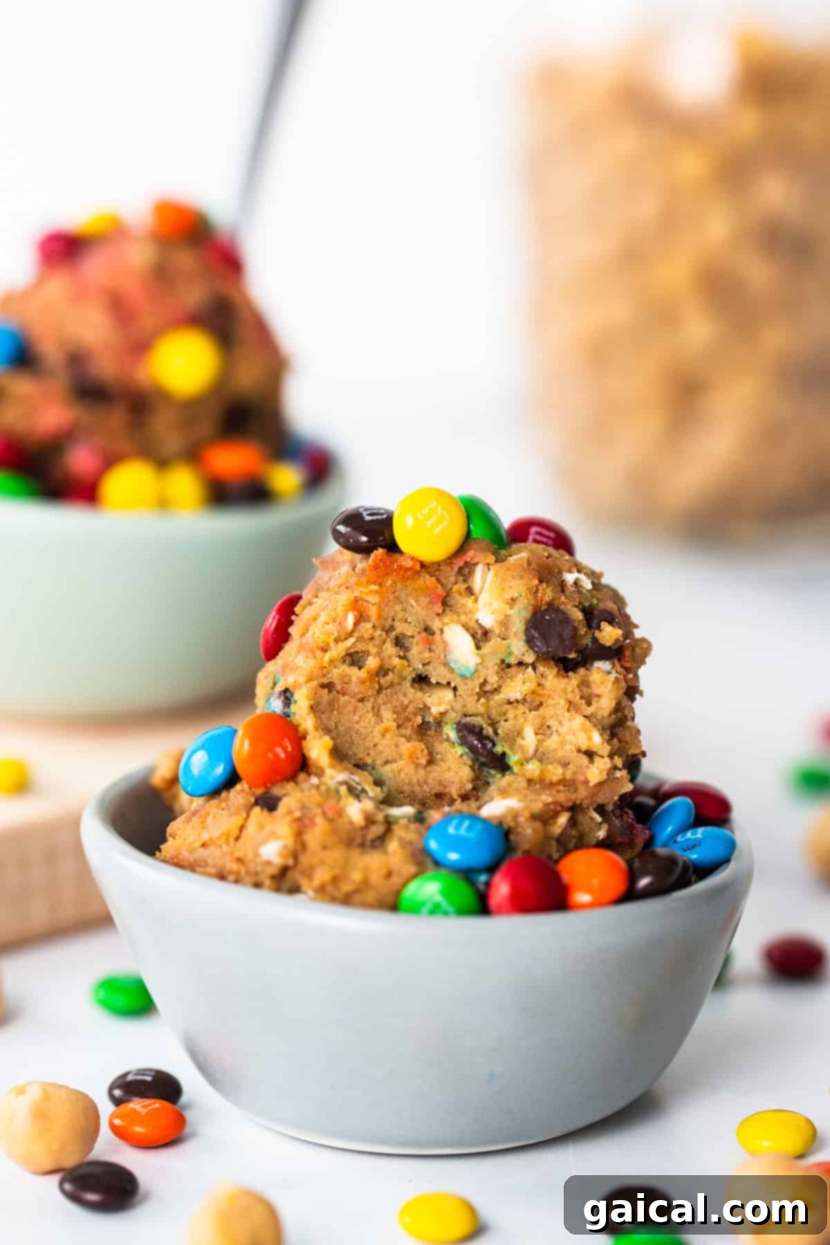Epic Protein Cookie Dough 2 A bowl filled with protein monster cookie dough, garnished with mini chocolate chips and M&Ms.