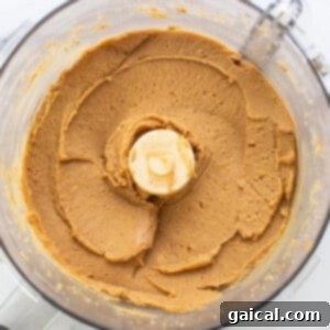 Peanut butter and other wet ingredients blending in a food processor.