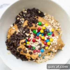 A white bowl filled with granola, oats and chocolate chips, ready to be added to the dough.