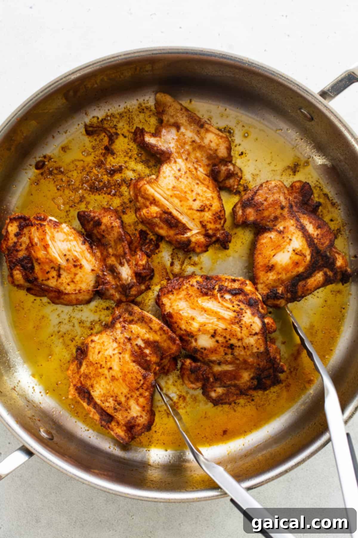 Two forks lifting a piece of perfectly seared chicken from a skillet filled with creamy street corn sauce.