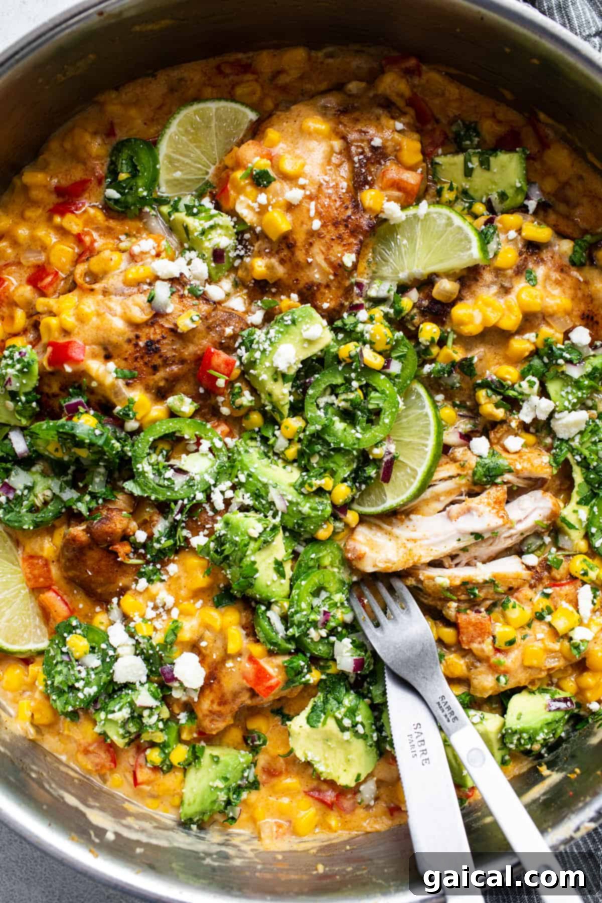 A large pan filled with creamy street corn chicken, ready to be topped with fresh slaw.