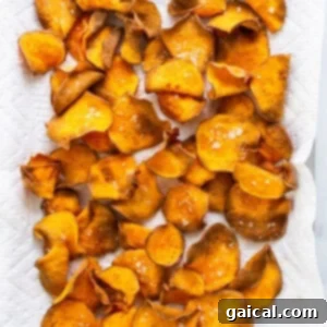 Freshly air-fried sweet potato chips spread on a baking sheet, showcasing their golden crispiness.