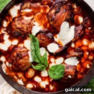 A skillet with chicken in a sauce with basil leaves.