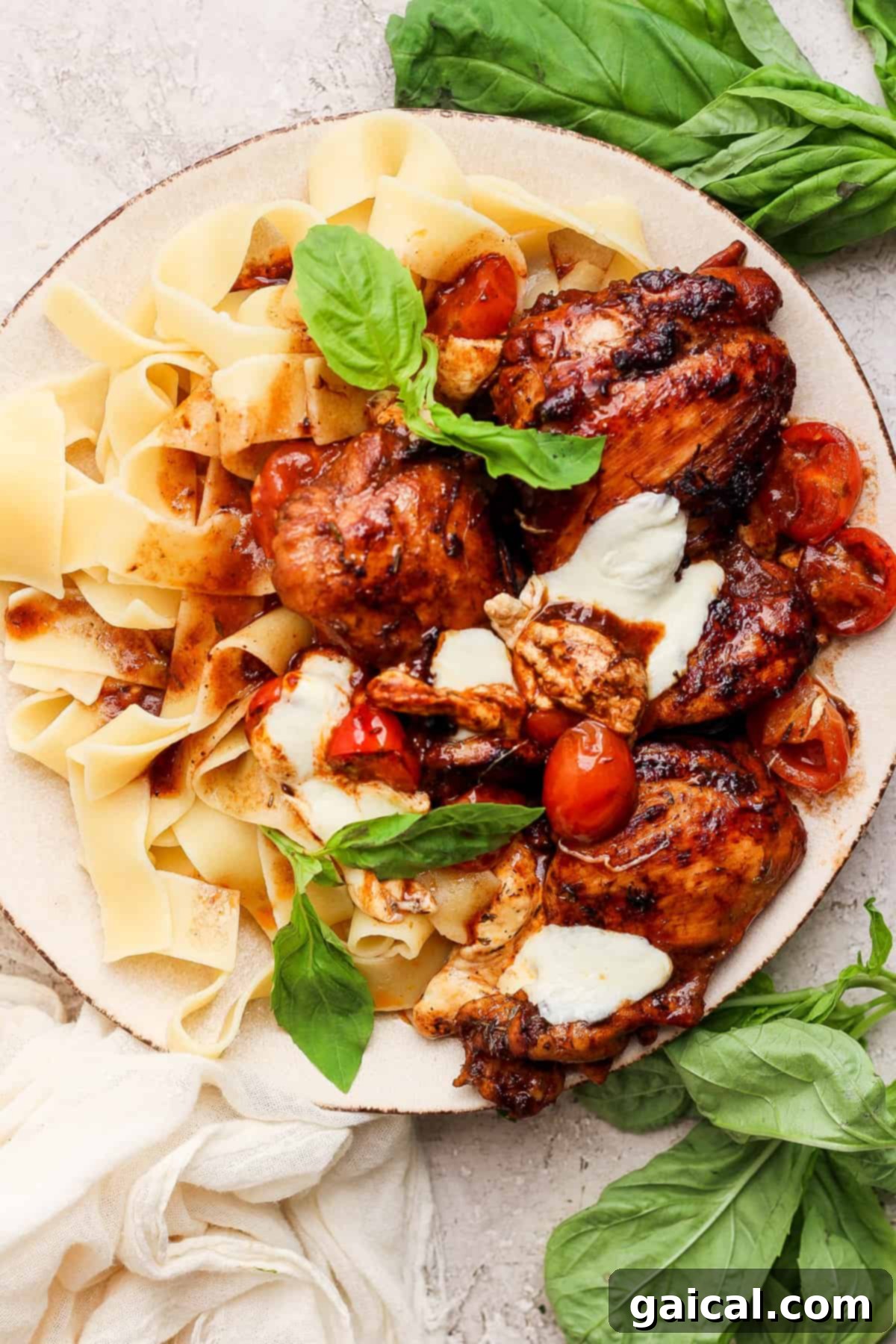 Rich Balsamic Glazed Chicken Thighs 8 A plate of pasta with chicken, tomatoes and basil.