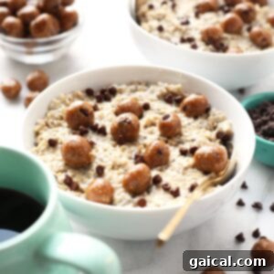 A bowl of creamy Chocolate Chip Cookie Dough Oatmeal, topped with mini chocolate chips, next to a cup of coffee.