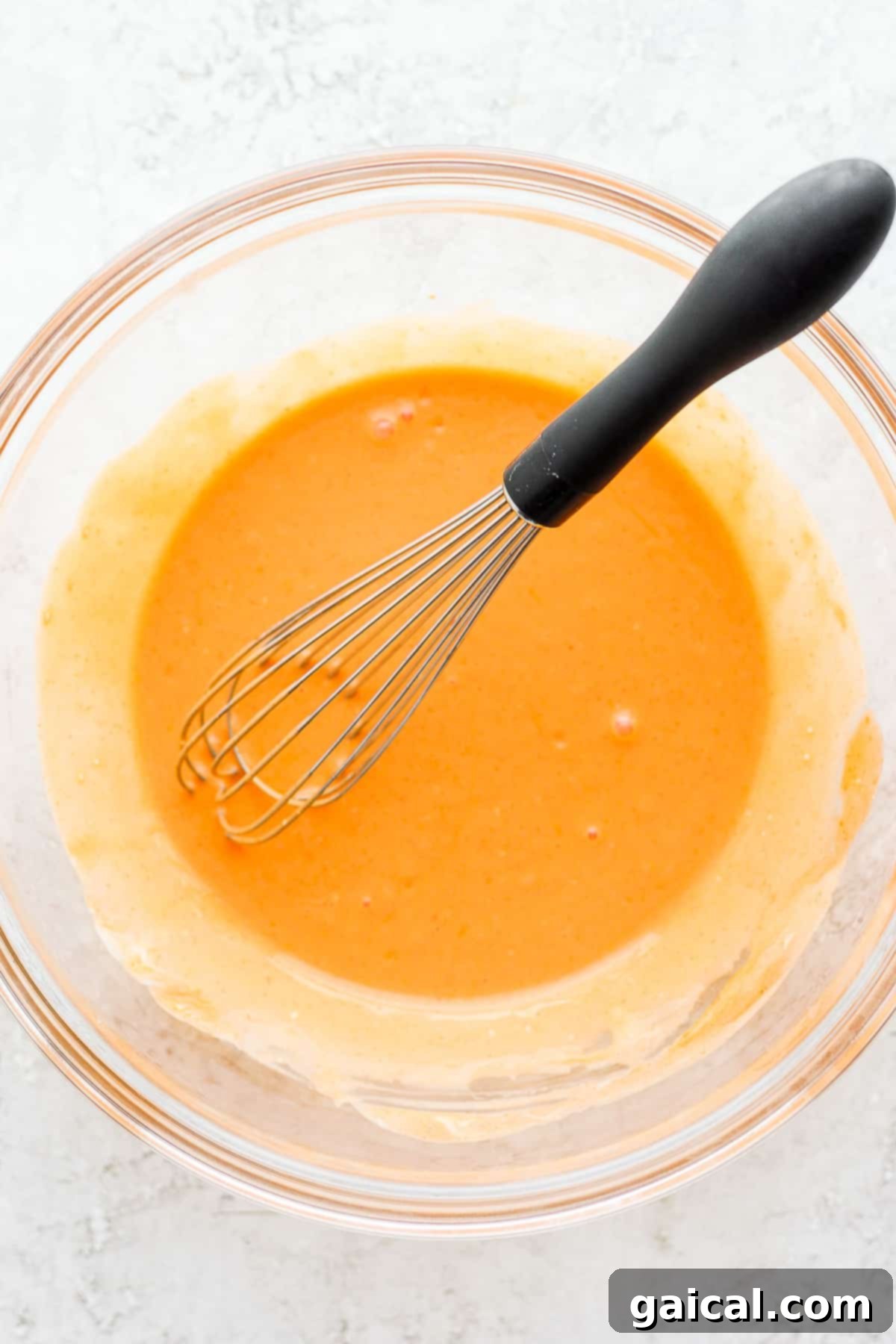 Homemade Buffalo Sauce for Chicken Wraps A bowl of vibrant buffalo sauce, freshly made and ready to coat shredded chicken, serving as a key ingredient for the buffalo chicken wrap.