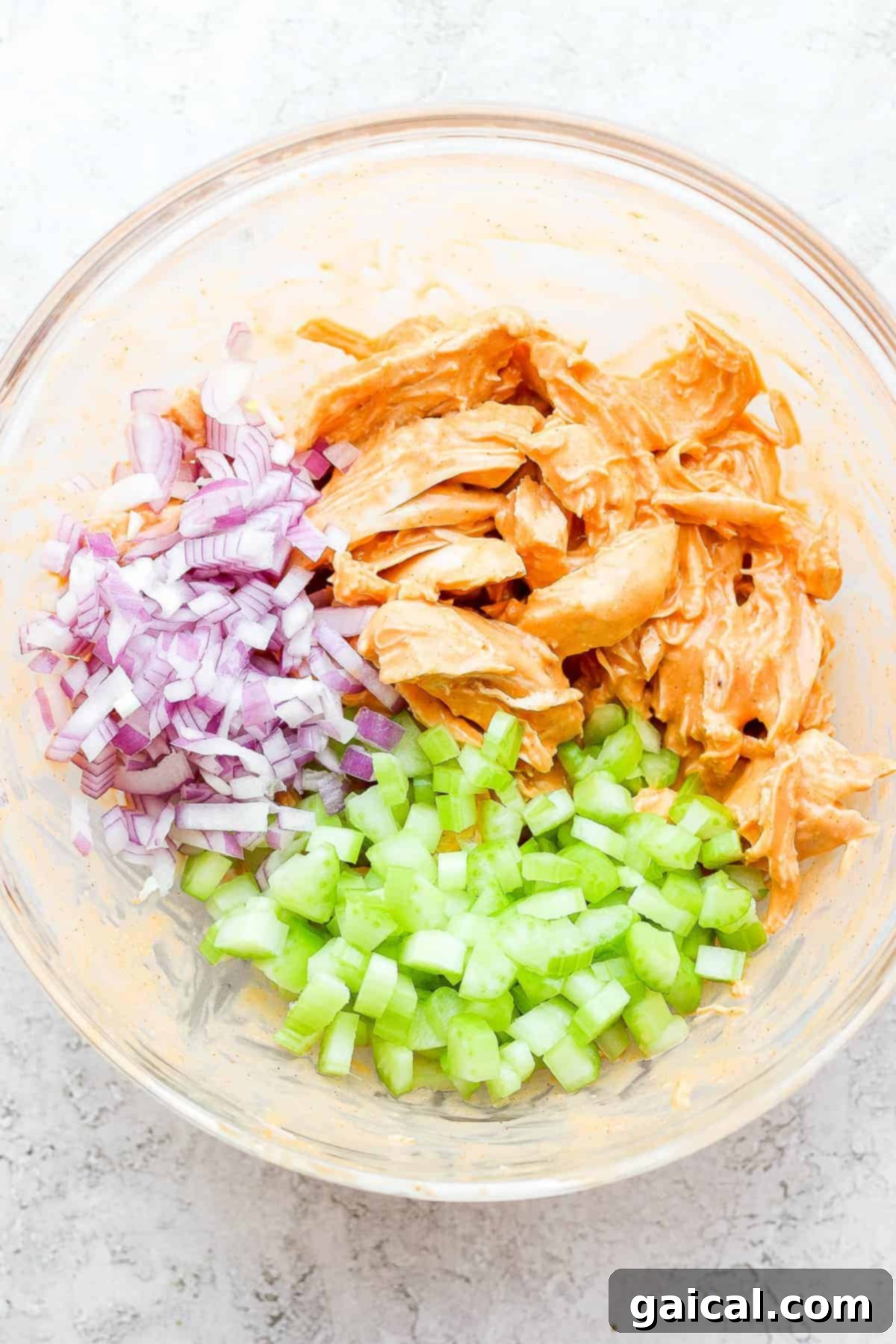 Prepared Buffalo Chicken for Wraps A bowl of delicious buffalo chicken mixture, perfectly prepared and ready to be wrapped in tortillas with fresh vegetables and blue cheese.