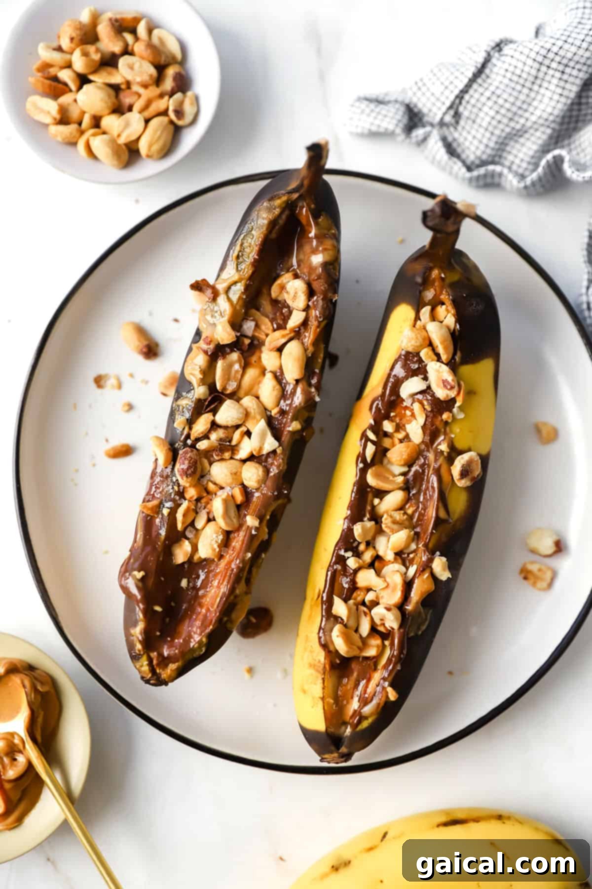 Air Fryer Roasted Banana Split 2 Two air fryer banana splits with peanut butter and nuts on a plate, ready to be enjoyed.