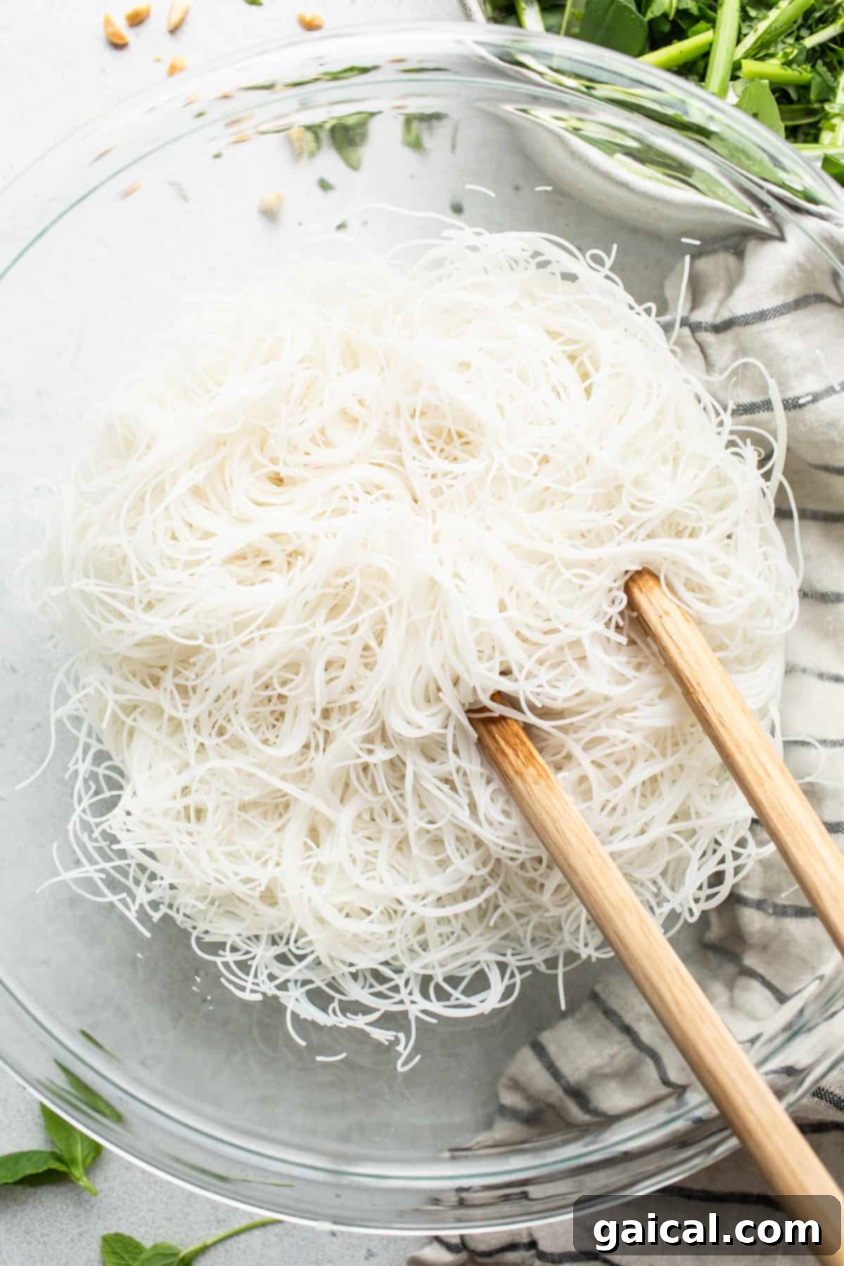 Fresh Spring Roll Bowl 3 A close-up photograph of perfectly cooked and cooled vermicelli noodles nestled in a pristine white bowl, accompanied by elegant chopsticks, poised to be transformed into a delectable salad.