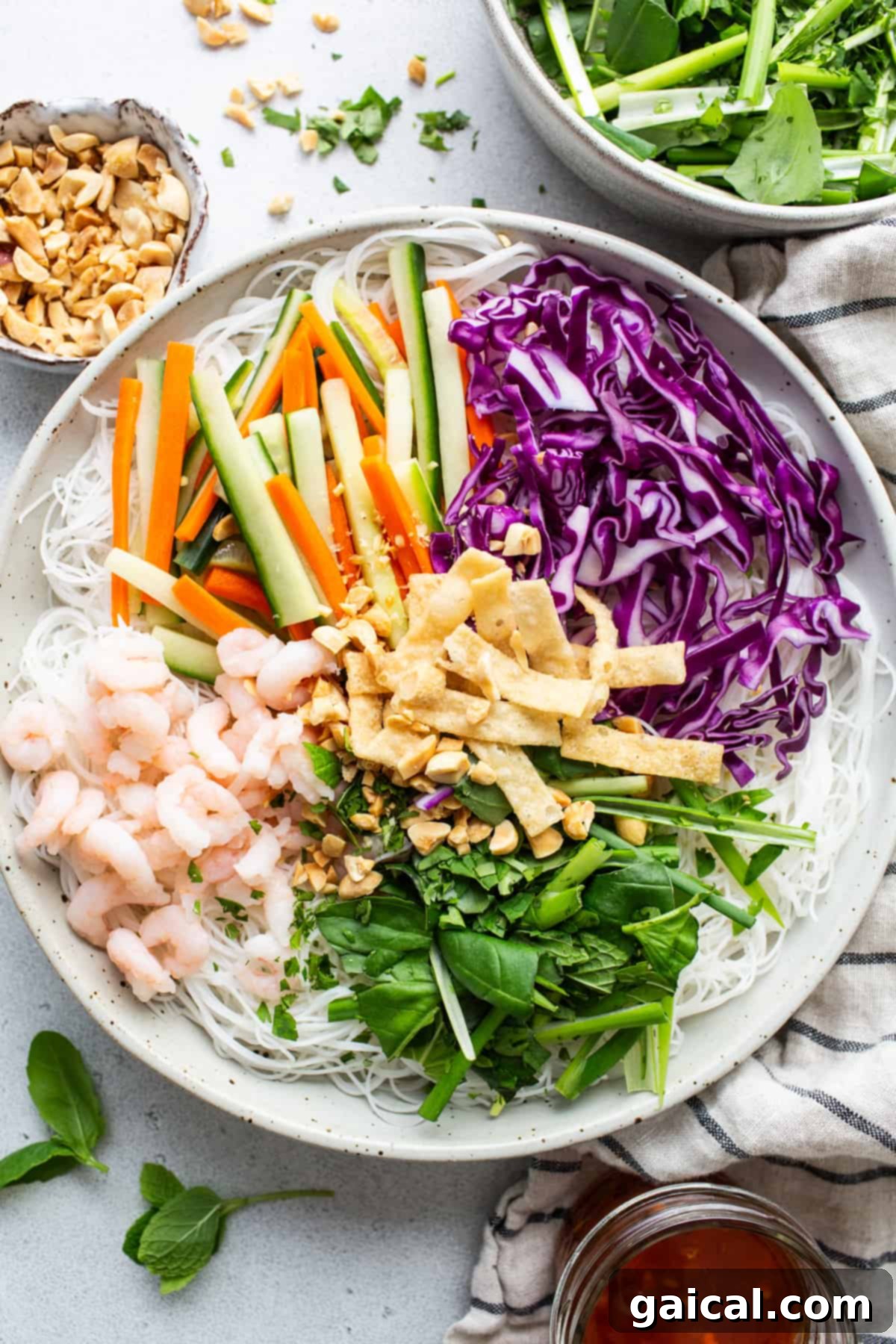 Fresh Spring Roll Bowl 4 A close-up, top-down view of a vibrant Vietnamese noodle salad, richly garnished with tender shrimp, an abundance of fresh herbs, and colorful, crunchy vegetables, emphasizing its appealing freshness and robust ingredients.