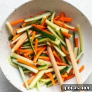 Fresh Spring Roll Bowl 8 Carrot and cucumber sticks marinating in a white bowl with a light dressing of rice vinegar and salt.