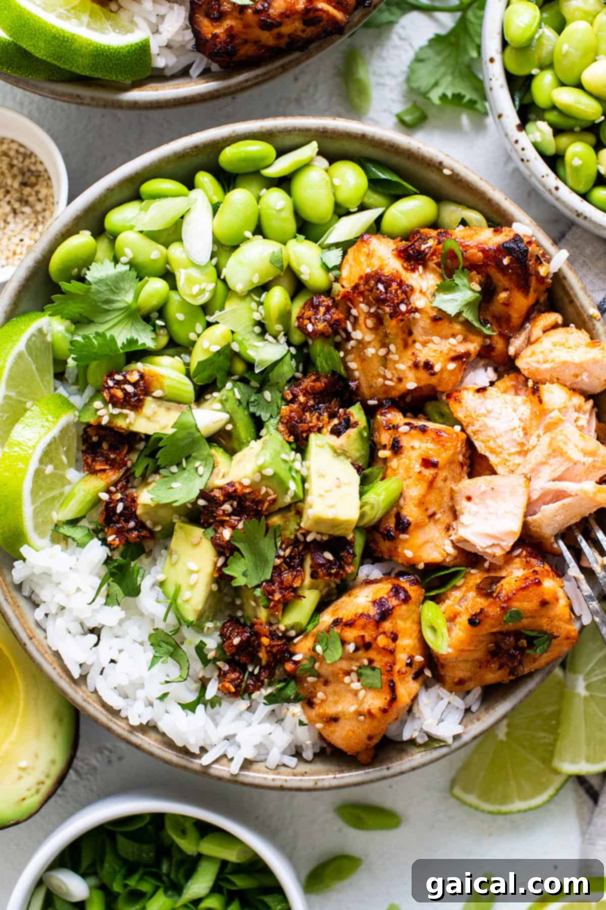 A vibrant and healthy meal featuring Honey Chili Crunch Salmon Bites, rice, fresh peas, and lime wedges, showcasing a complete serving suggestion.