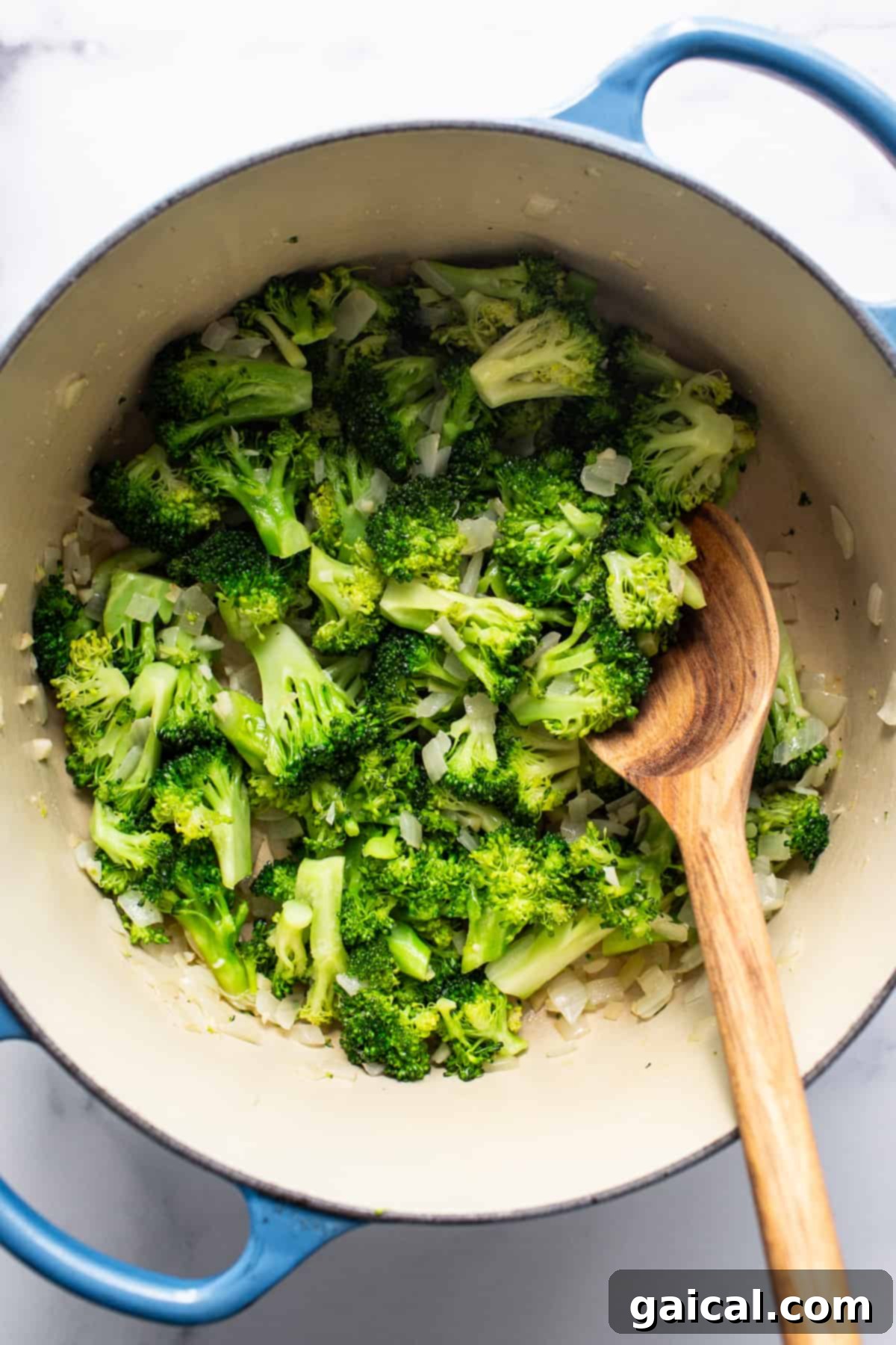 Velvety Broccoli Pasta 3 Fresh broccoli florets in a blue pot with a wooden spoon, ready for cooking.