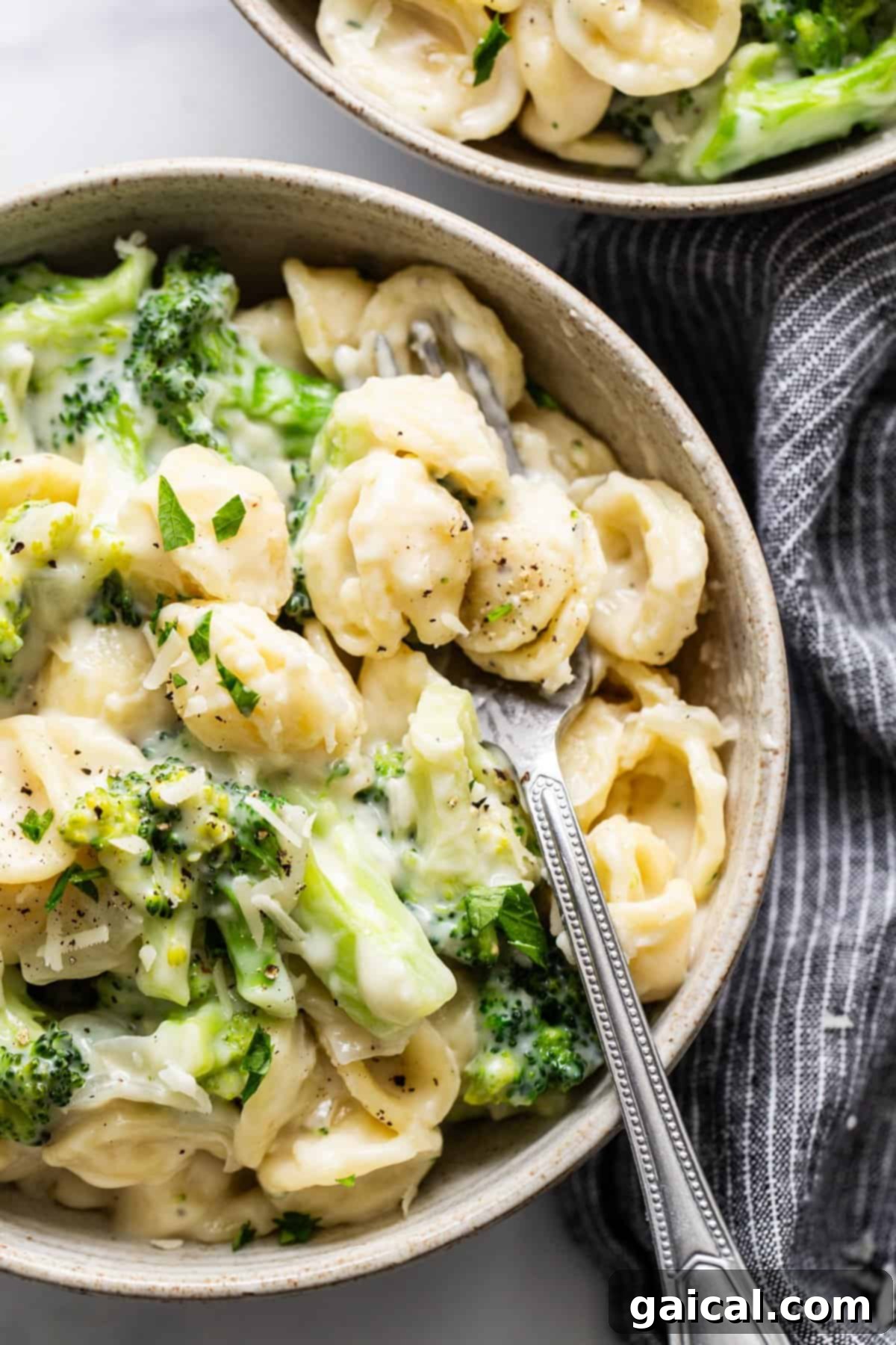 Velvety Broccoli Pasta 5 Two bowls of pasta with broccoli and cheese, garnished with fresh herbs.