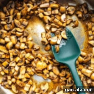Mushrooms in a pan with a green spatula.