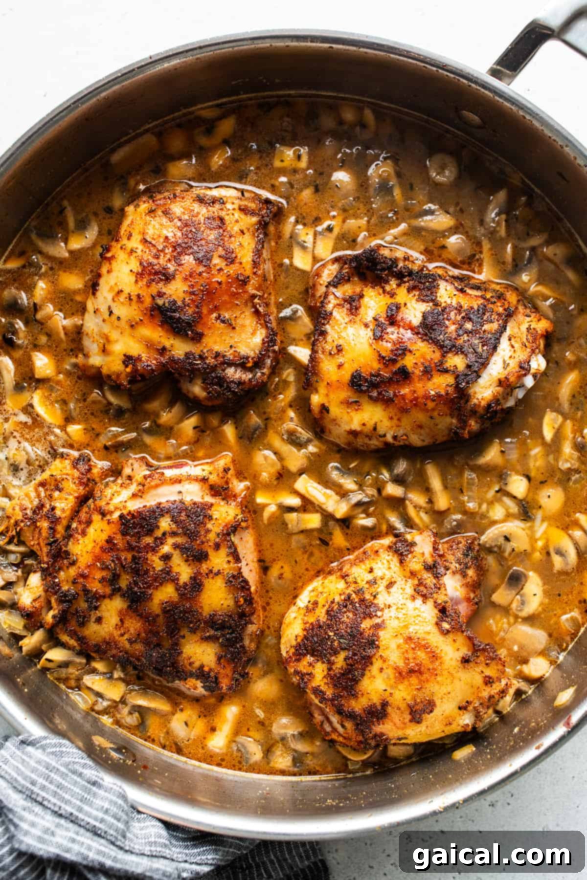 Chicken breasts in a pan with mushrooms and tomatoes.