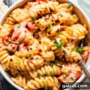 Irresistible Roasted Garlic Boursin Melt 3 A bowl of creamy pasta with tomato pieces and sprinkled with herbs.