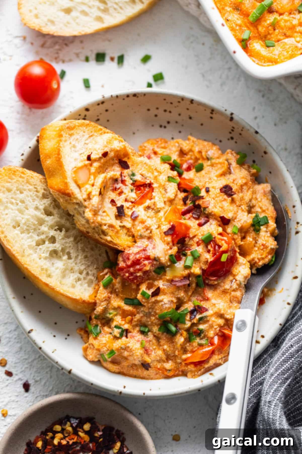 Irresistible Roasted Garlic Boursin Melt 8 A beautifully plated serving of Roasted Garlic Baked Boursin Dip, garnished with fresh chives and red pepper flakes, served with an assortment of dippers.
