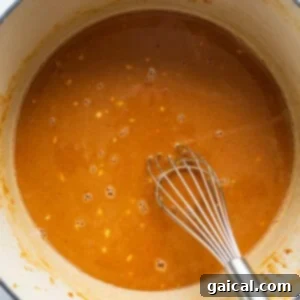A pot of creamy peanut sauce being whisked to perfection, ready to be heated and combined with the cooked noodles.