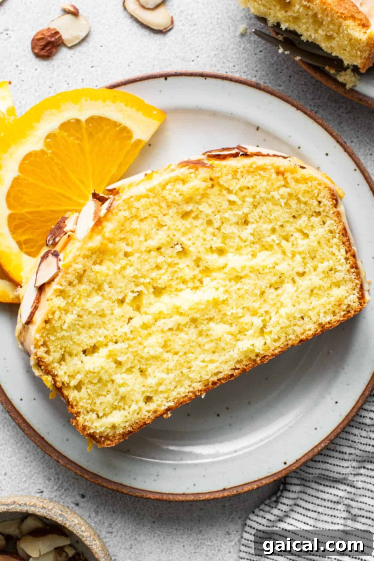 Sun-Kissed Orange Cake 6 A slice of orange cake with almonds on a plate.