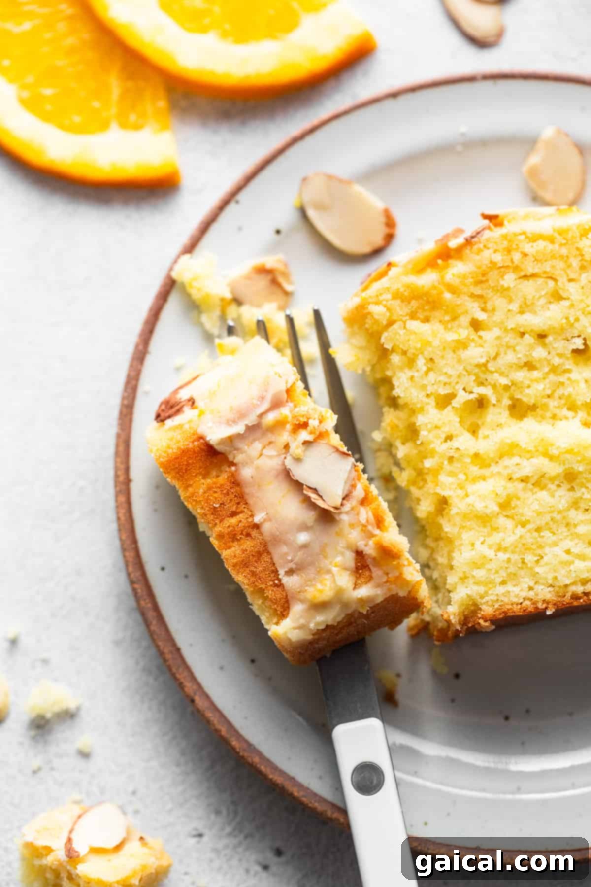 Sun-Kissed Orange Cake 7 A slice of orange cake with almonds on a plate.