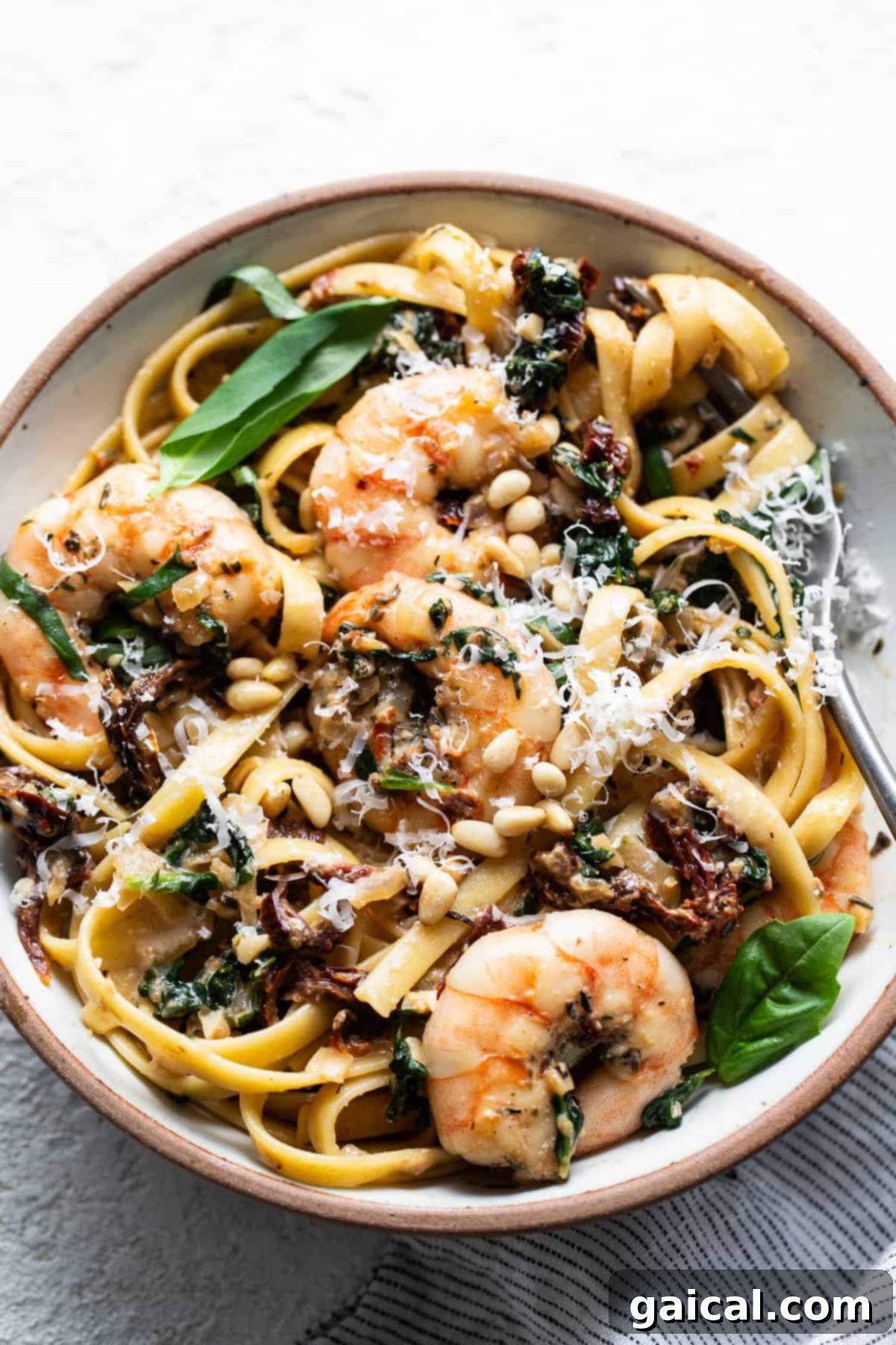 Creamy Tuscan Shrimp Linguini 2 A bowl of creamy Tuscan shrimp linguini with mushrooms and spinach, garnished with fresh herbs.
