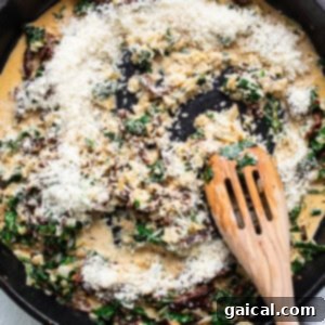 Creamy Tuscan Shrimp Linguini 9 A skillet filled with spinach and cheese, being stirred with a wooden spoon.