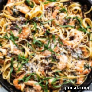 Creamy Tuscan Shrimp Linguini 10 A skillet filled with pasta and shrimp, coated in a creamy sauce.