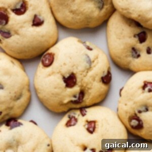 A group of perfectly baked chocolate chip cookies arranged on a pristine white surface, highlighting their golden edges and melty chocolate centers, inviting a delicious treat.
