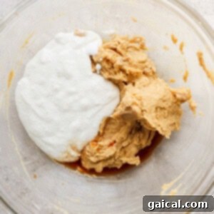 The combined wet ingredients for peanut butter cookie dough in a clear glass bowl, showcasing a smooth, creamy texture.