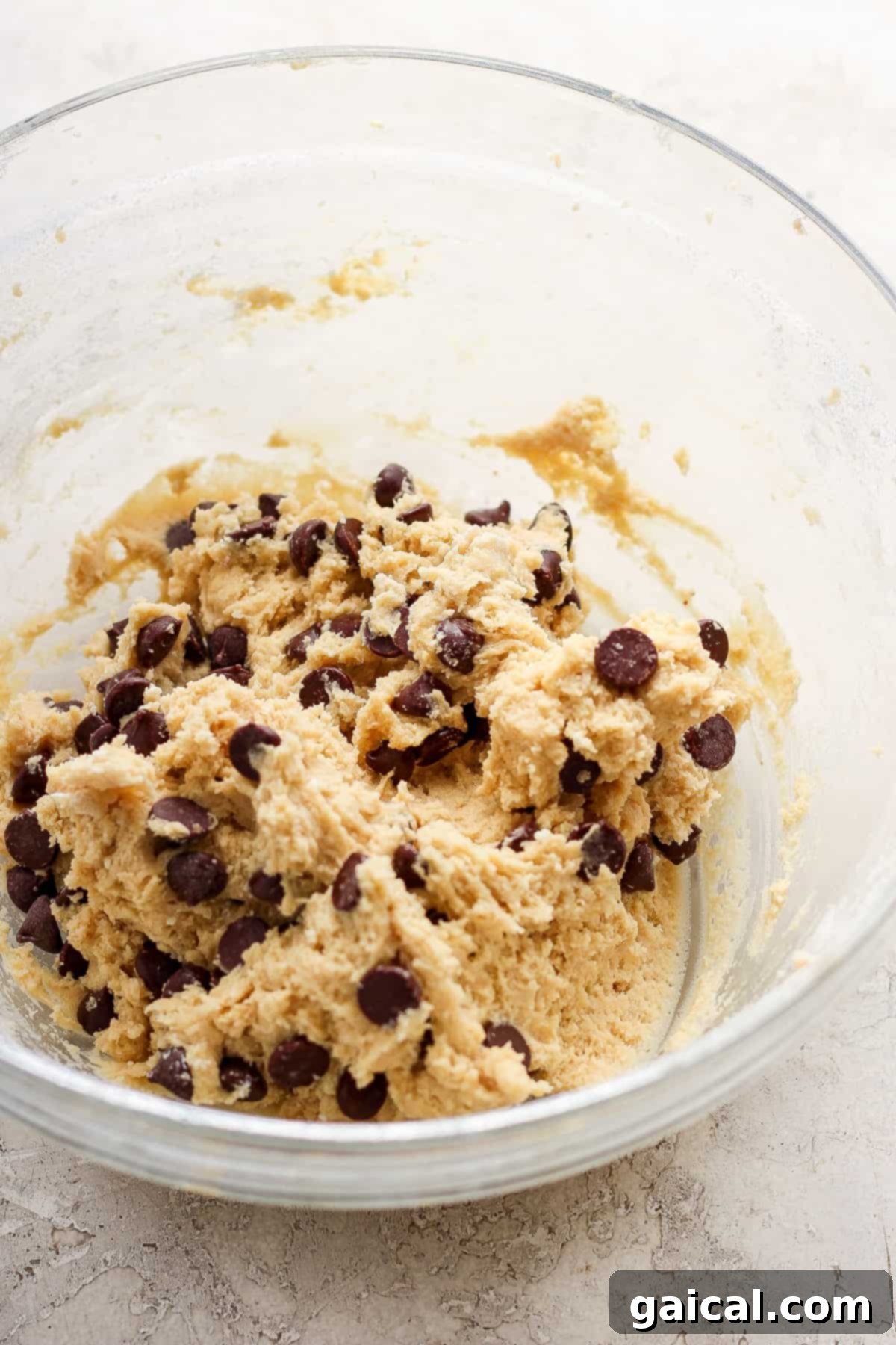 A pristine bowl filled with perfectly mixed chocolate chip cookie dough, featuring visible chocolate morsels, patiently awaiting its transformation in the oven.
