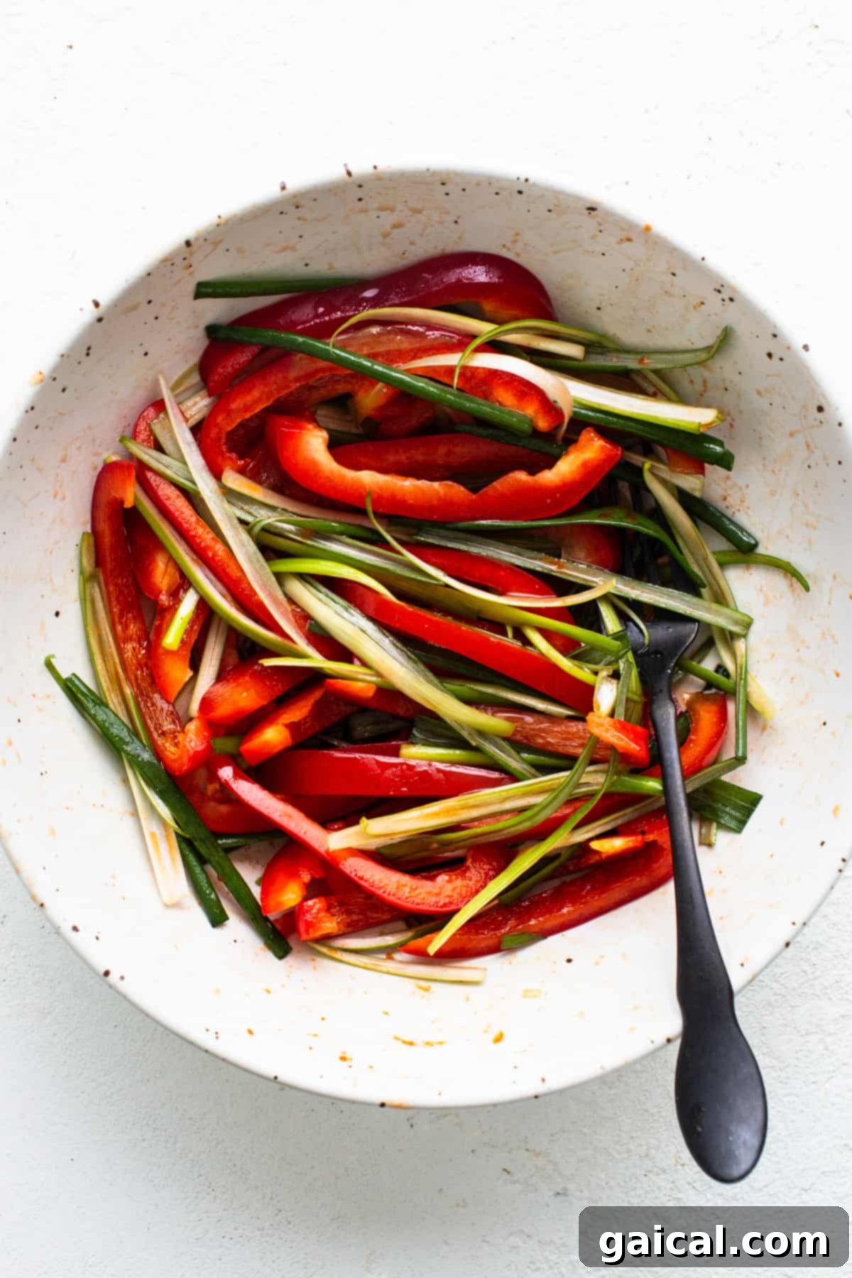 Sweet and Spicy Korean Ground Beef 4 A bowl of sliced red bell peppers and green beans ready for cooking with Korean ground beef, accompanied by a spoon.
