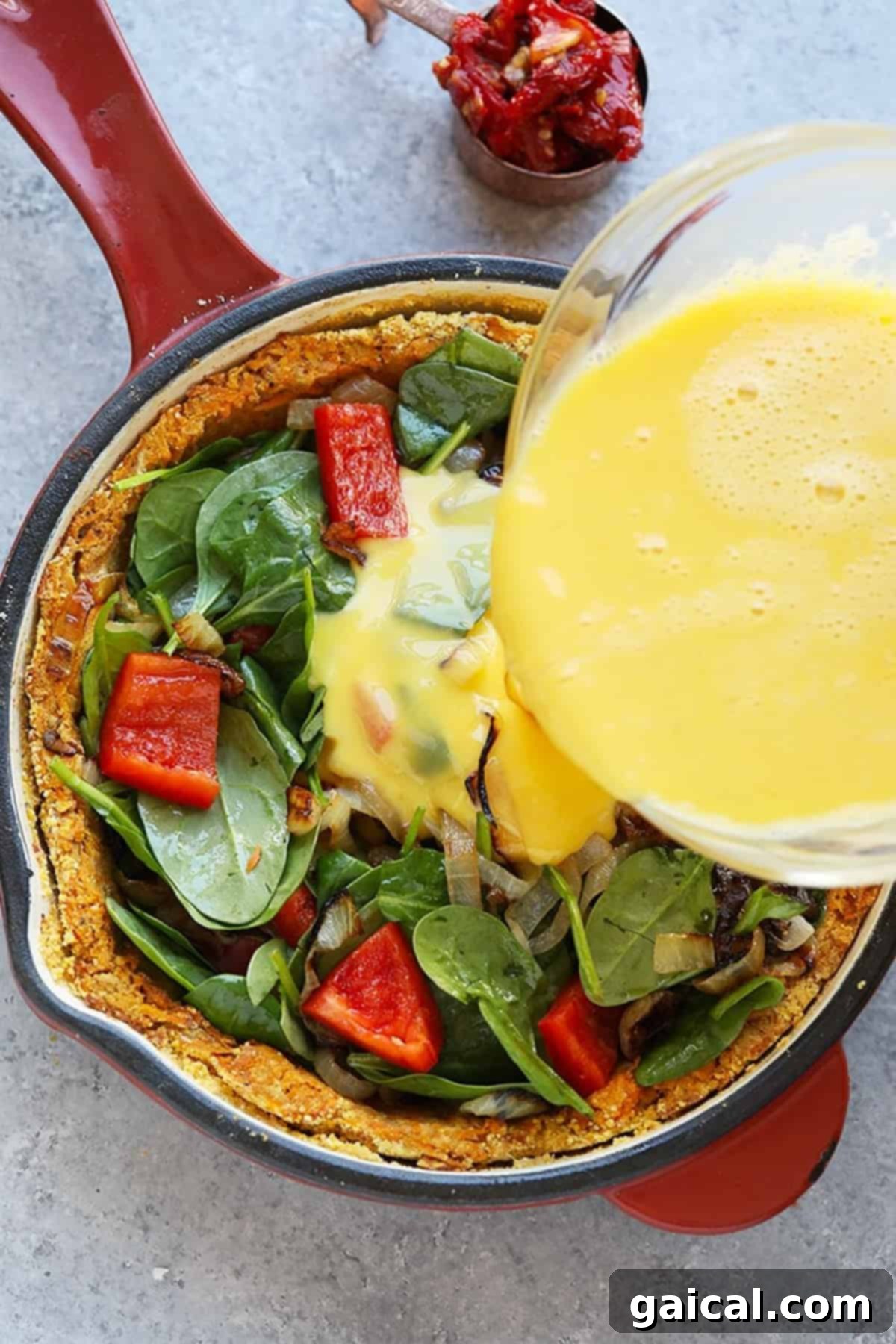 Vibrant Eats Collective: March 2024 4 a skillet filled with a spinach and egg quiche being poured with a sauce.