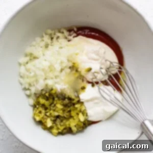 A bowl of ingredients with a whisk in it, combining to make the dressing.