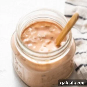 A jar of homemade Thousand Island dressing with a wooden spoon, showcasing its perfect consistency for serving.
