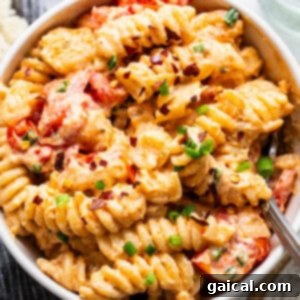 A bowl of creamy pasta with tomato pieces and sprinkled with herbs.