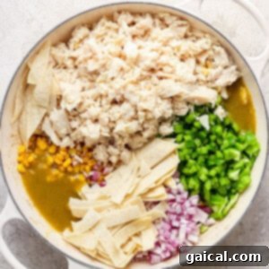 Mexican chicken enchiladas in a pan with corn and peas, cooking on the stovetop.