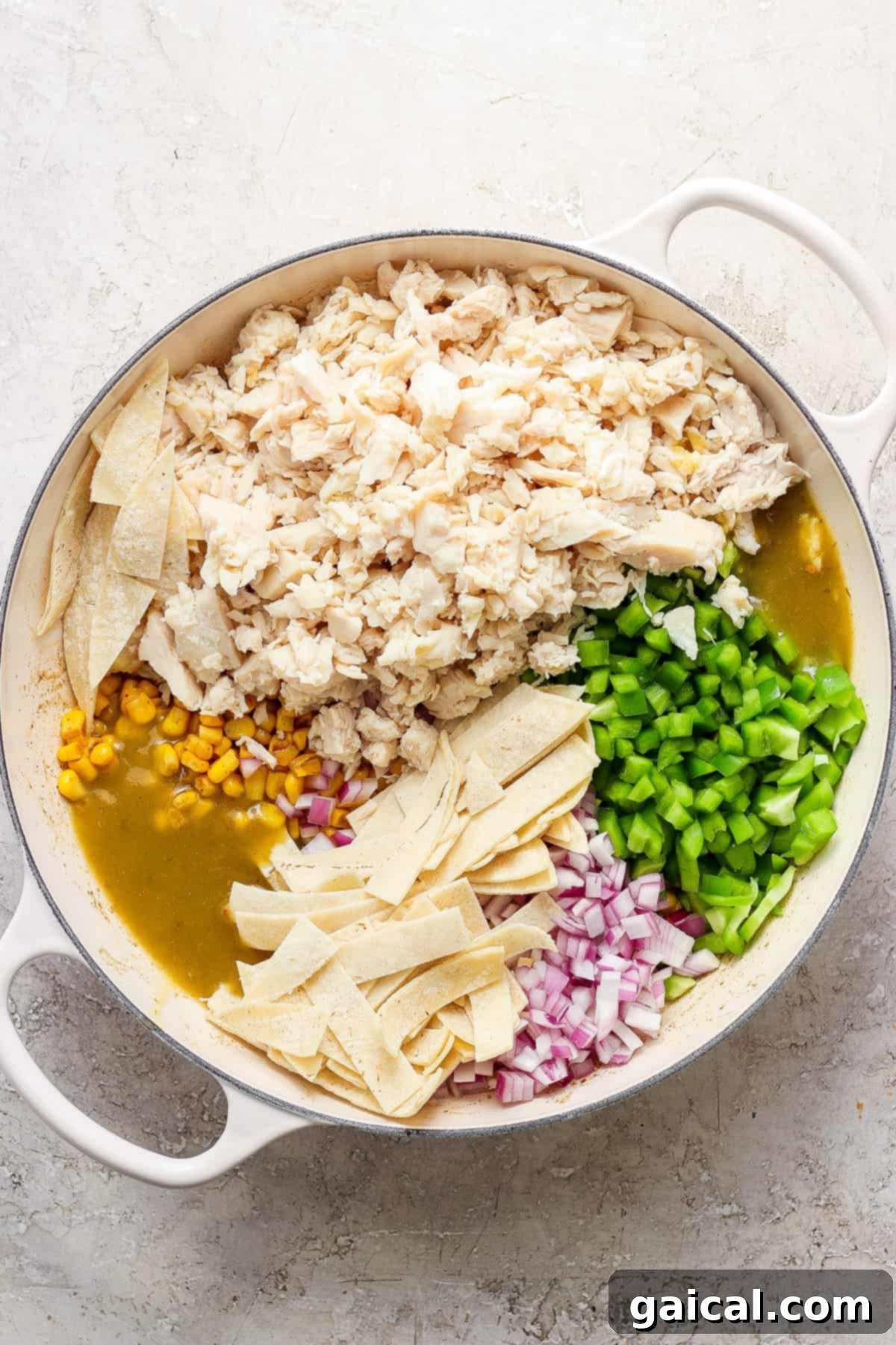 Mexican chicken enchiladas in a pan with corn, green bell pepper, and sauce.