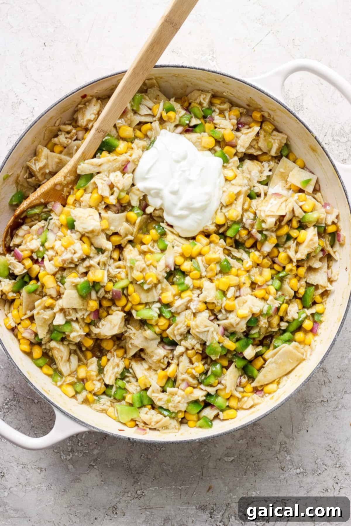 A skillet filled with caramelized corn, sauce, and a dollop of sour cream.