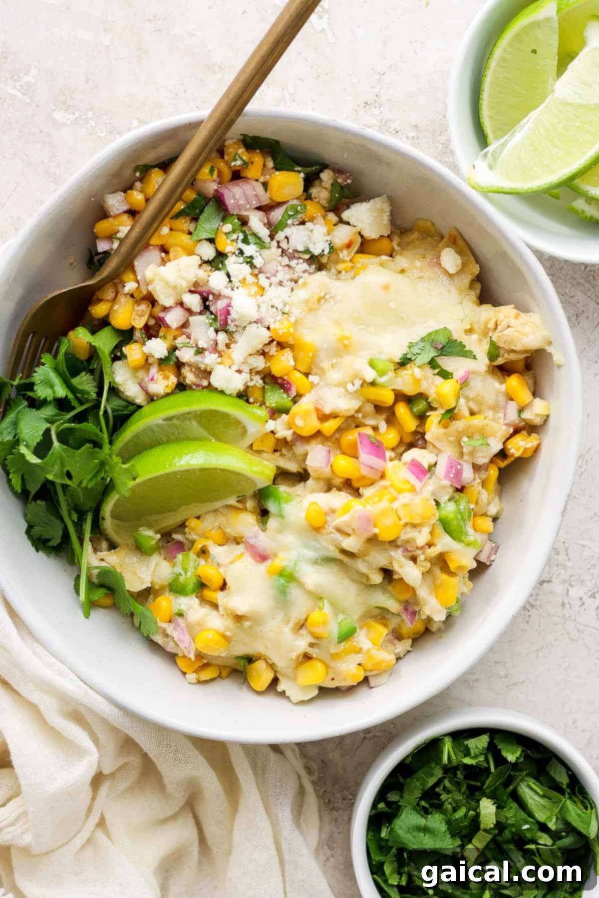 Mexican chicken and corn enchiladas served in a white bowl, garnished with cilantro.