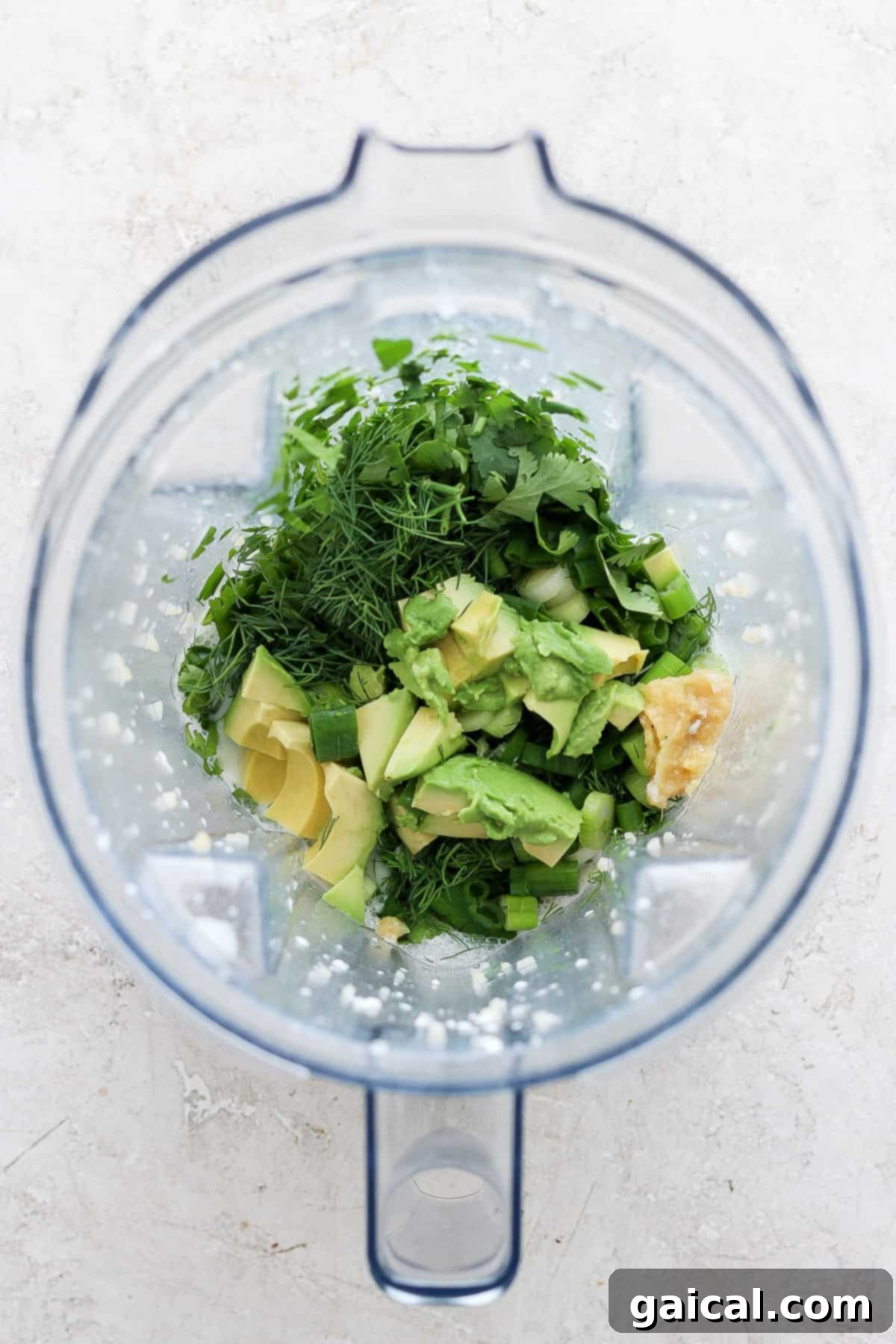 Vibrant Green Goddess Quinoa Bowl 4 Ingredients including herbs, avocado, and banana prepared in a blender ready for blending.