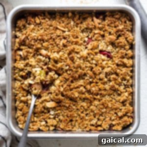 A golden-brown rhubarb crisp fresh out of the oven, bubbling along the edges in a glass baking dish, ready to cool.
